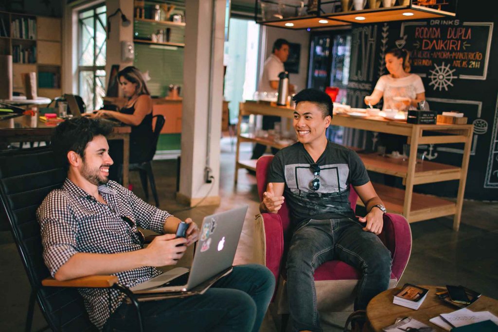 Two men sitting in a coffee shop with laptops.